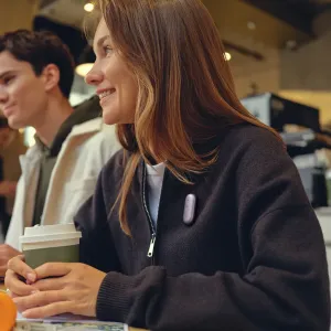 PLAUD NotePin S enregistreur vocal violet à pince porté sur une veste dans un café