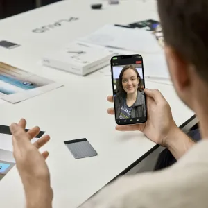 PLAUD Note Pro voice recorder beside a smartphone during a video call on a white table