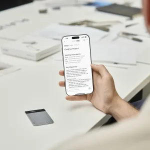 PLAUD Note Pro voice recorder beside a smartphone showing AI meeting notes and summaries