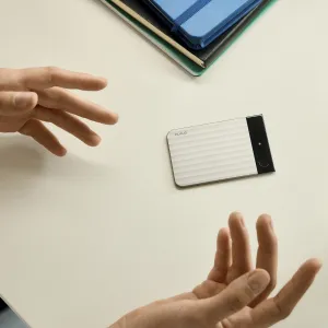 PLAUD Note Pro voice recorder with AI transcription, shown compact and magnetic on a desk with hands nearby.