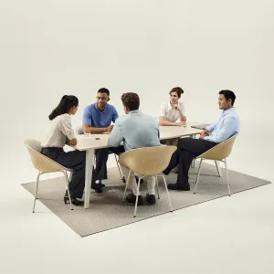 Grabadora de voz con IA PLAUD Note Pro sobre una mesa de reuniones durante una discusión grupal presencial