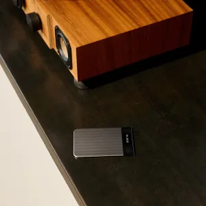 Grabadora de voz con IA PLAUD Note Pro con cuerpo slim gris, panel negro en el extremo y marca PLAUD sobre una mesa