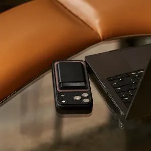 PLAUD Note Pro, grabadora de voz con IA, acoplada a un smartphone junto a un portátil sobre una mesa de cristal
