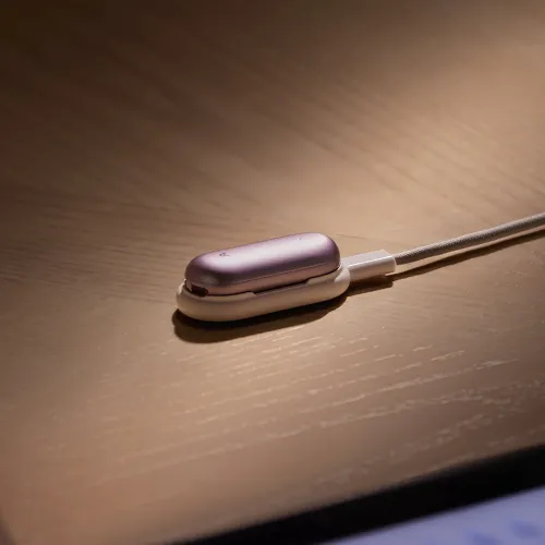 PLAUD NotePin in Sunset Purple liegt horizontal auf einer weißen Ladestation, die mit einem angeschlossenen USB-C-Kabel verbunden ist, und steht auf einer Holzoberfläche.