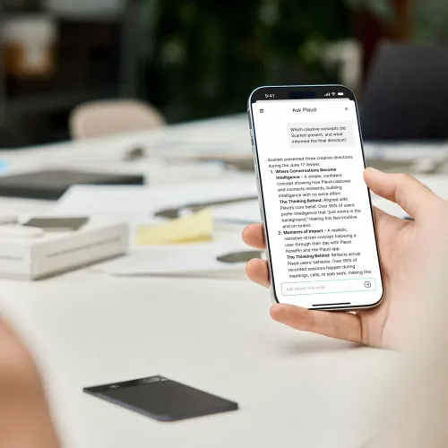 PLAUD Note Pro app on a smartphone beside the black recorder device in a meeting setting